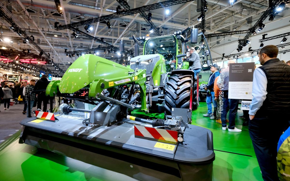 Landwirtschaftsmesse mit einem ausgestellten Fendt-Traktor und Frontmähwerk; Besucher betrachten die Maschine.